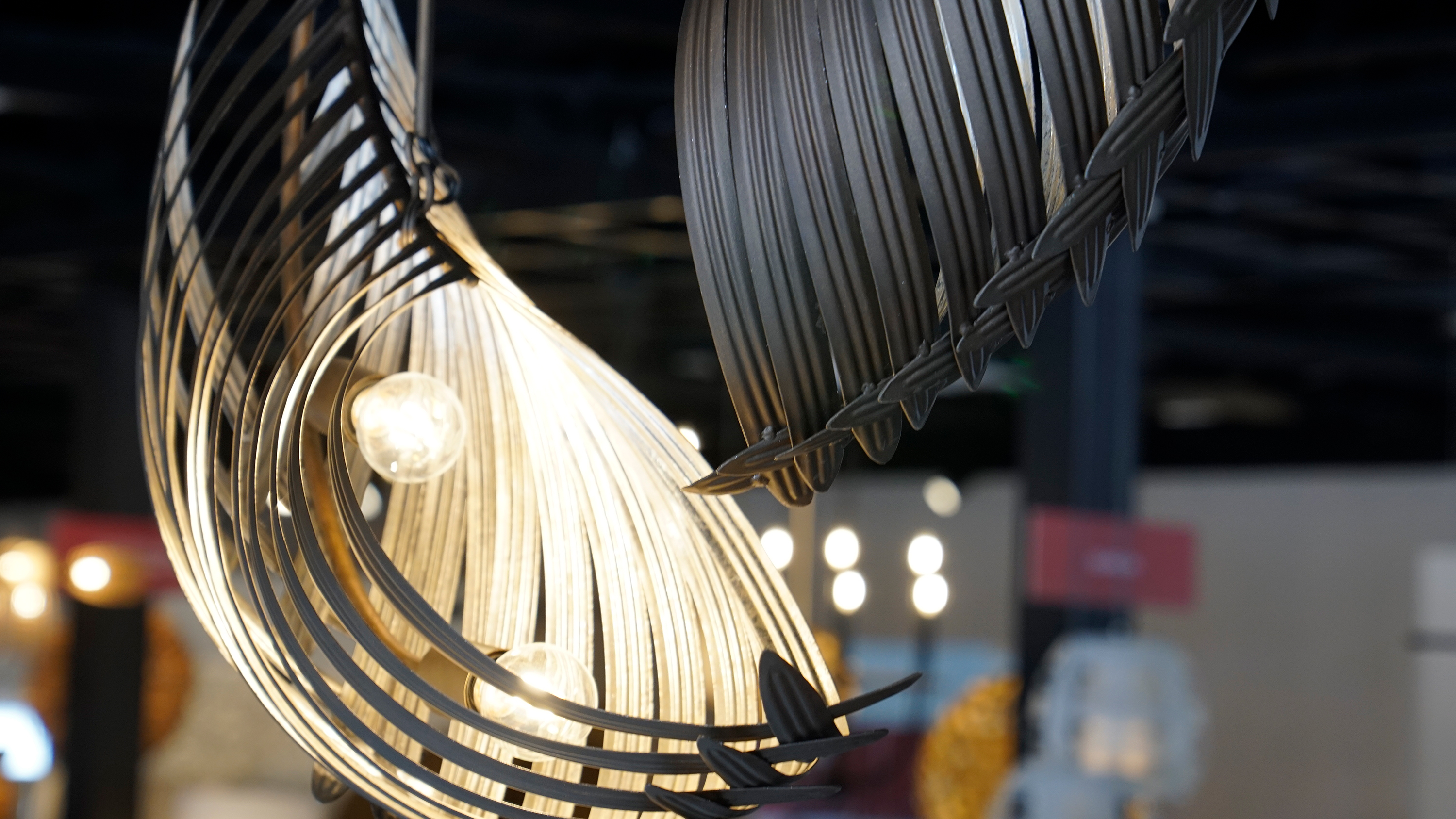 Curved, leaf-shaped black metal pendant lights illuminated from within.