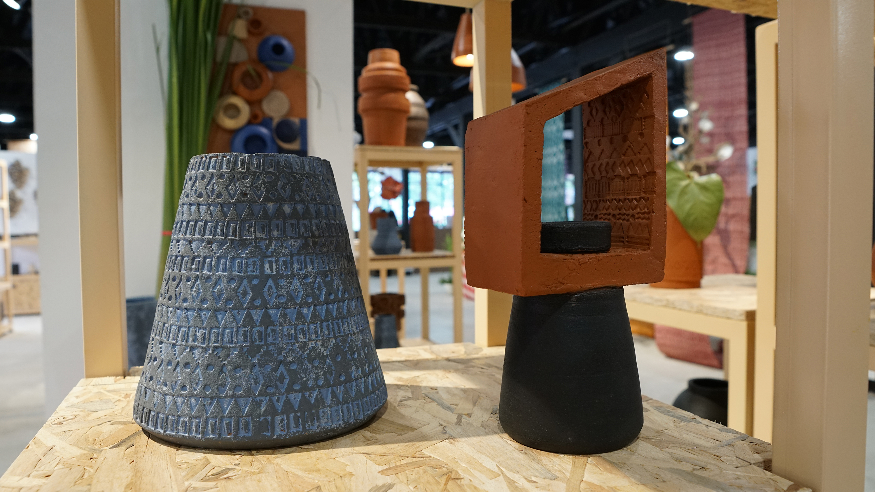 A textured blue cone-shaped vase next to an abstract black and terracotta sculpture.